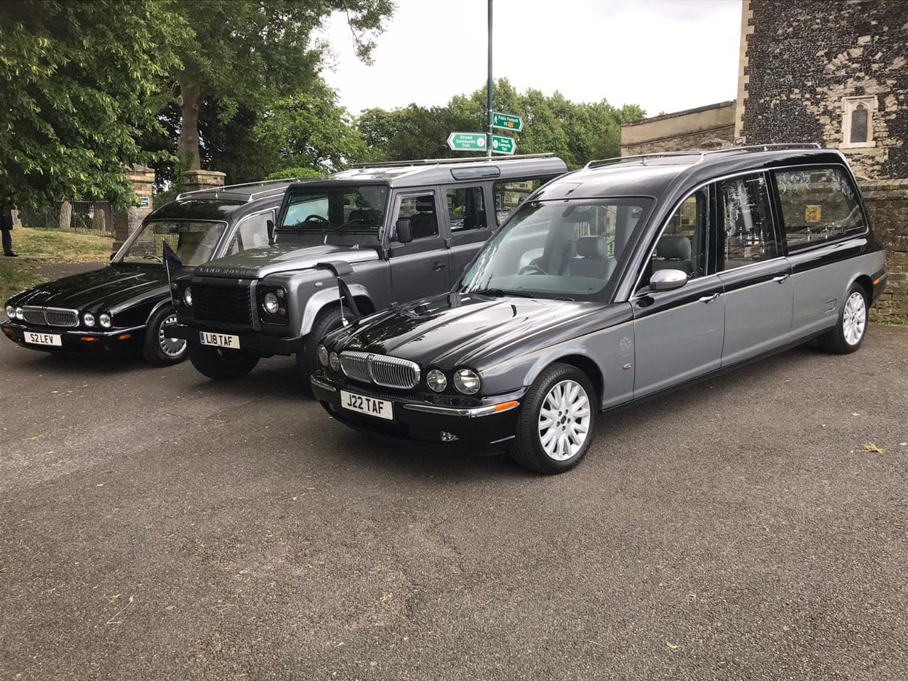 A trio of Terry Allen cars with a Classic Land Rover parked in the middle outside a church